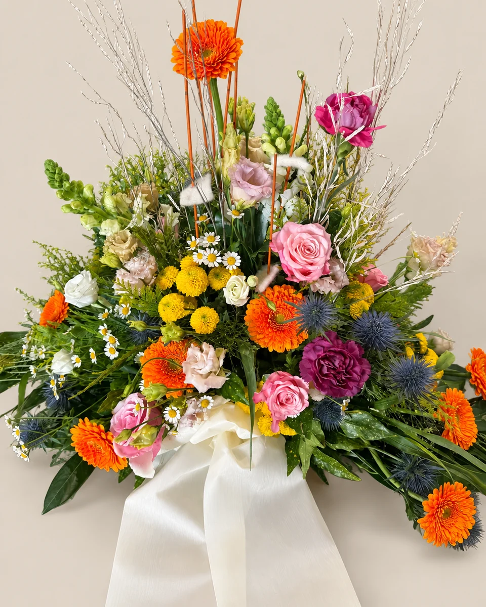 B02: Gesteck in Gelb, Orange und Rosa.