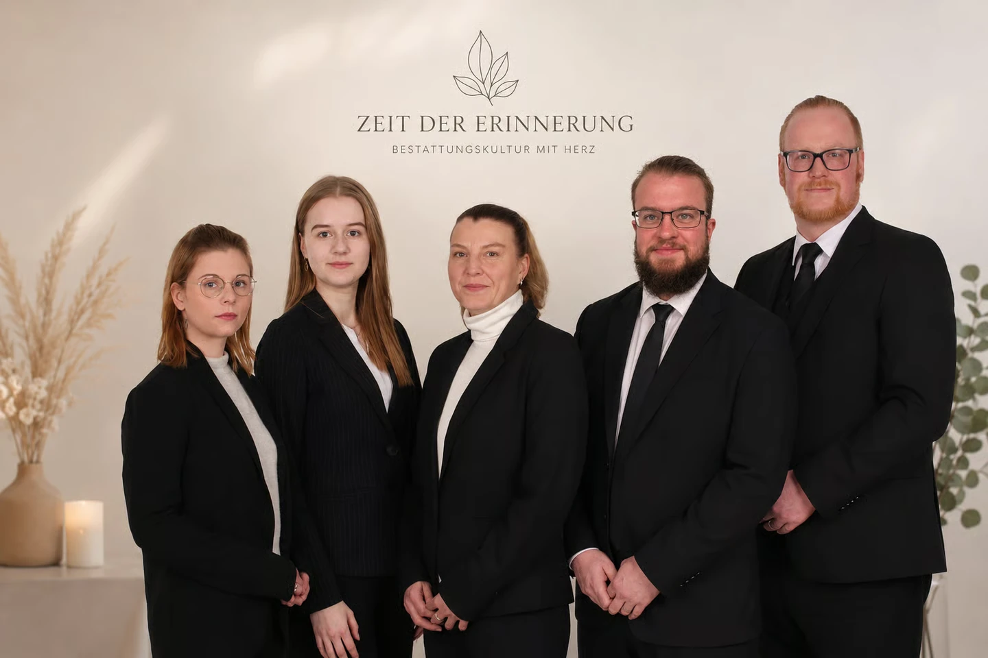 Fünf Mitarbeitende von Bestattungen Jansen & Schröder vor dem Schriftzug Zeit der Erinnerung